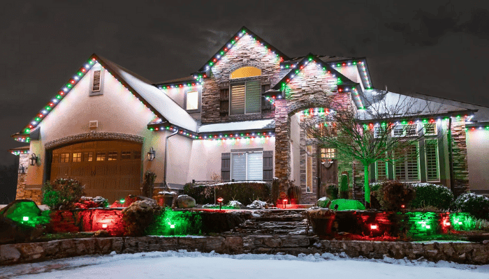 Two-story home decorated with colorful Jellyfish Lighting permanent LED lights along the roofline during winter.